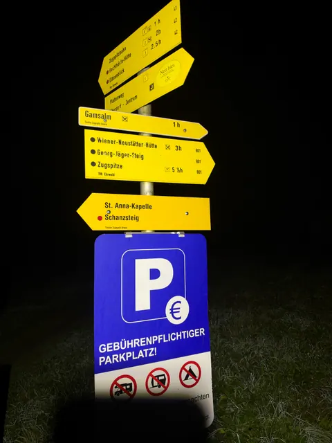 Gelbe Wanderwegweiser nach Ehrwald und zur Zugspitze im Licht der Stirnlampe