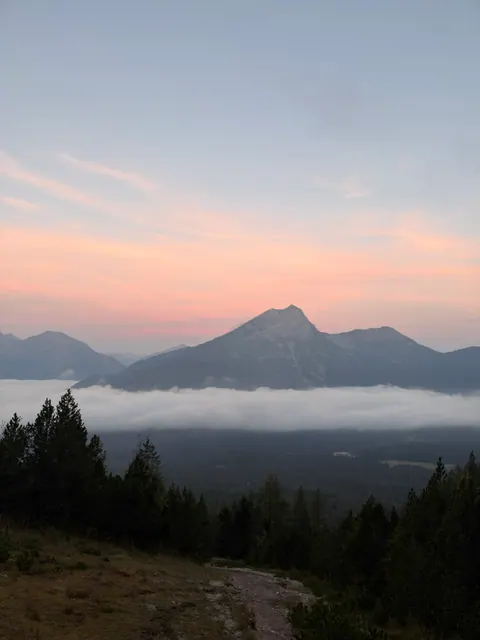 Rosa Morgenhimmel über den Bergen und einem Wolkenmeer