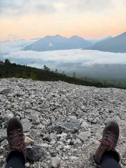Wanderschuhe bei einer Pause auf Geröll mit Blick über die Wolken im Tal