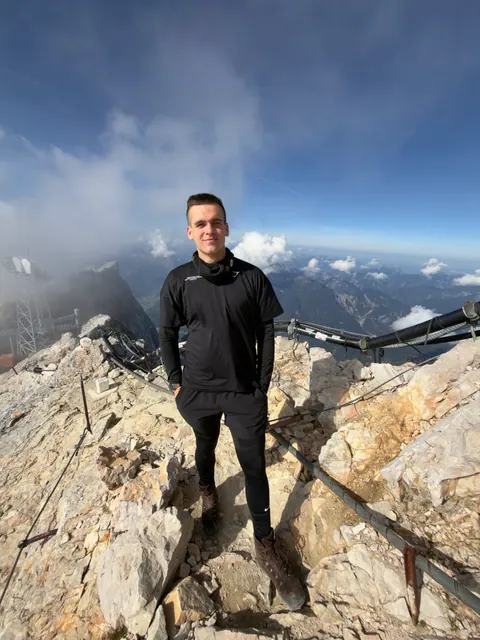 Ben im felsigen Gipfelbereich der Zugspitze neben einer Seilsicherung